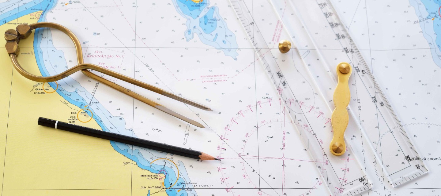 Antique W HC 6" brass dividers calipers nautical navigation chart tool, pencil, parallel ruler, old white chart close-up.