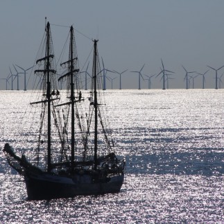 old sailing boat infront of a wind farm